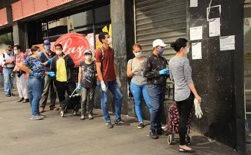 People wearing protective masks while waiting for turns to enter a supermarket during the COVID-19 pandemic in Caracas. Venezuela, 2020. Image by Edgloris Marys / Shutterstock.