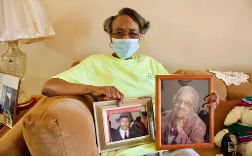 Valerie Nichols poses with photos of her mother, Willie Mae Nichols, and father, Anthony Nichols at her home in Preservation Square. Her father is deceased and her mother is living at Grand Manor Nursing and Rehabilitation Center. Image by Wiley Price/St. Louis American. United States, 2020.