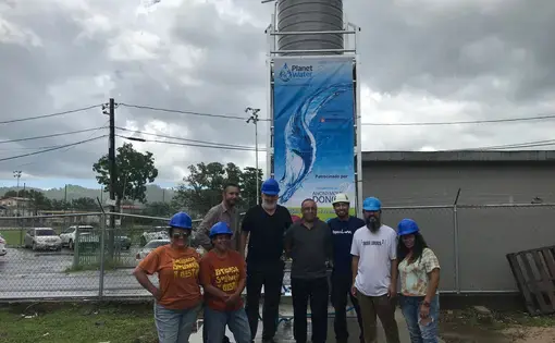 After a whole day of work, members of Brigada Solidaria and Rayo De Luna stand in front of the water tower they installed, which will provide&nbsp;Añasco residents and students of the Escuela Espino elementary school with filtered water. Image by Tomas Woodall Posada. United States, 2018.