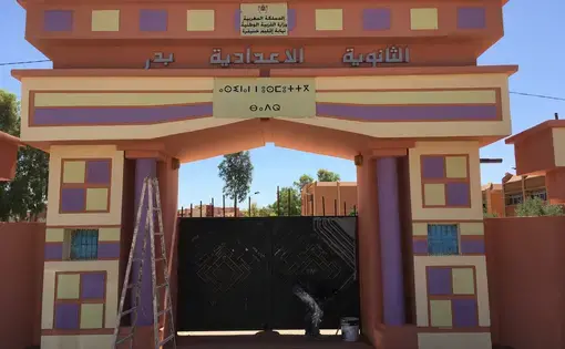 Workman adds finishing touches to the entrance to a Moroccan middle school. Morocco's new Minister of Education, Mohamed Hassad, has begun his tenure with a focus on achieving immediate results in advancing an ambitious program of reform, including significant changes to Morocco's language education policies. Another initial measure he took was to order all primary and middle schools to be repainted in bright pastels for the beginning of the school year, pictured here. Image by Gareth Smail. Morocco, 2017.