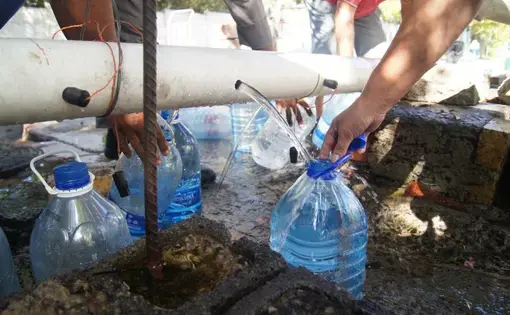 Residents collect water from a makeshift and unregulated water source at Springs Way. Image by Jacqueline Flynn. South Africa, 2018.