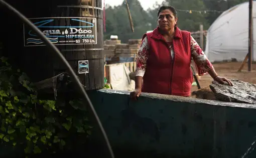 Margarita Reyes takes a break after finishing her typical water gathering routine, which requires her to haul a large pump down to a nearby river. Reyes has lived on the same property her entire life and has watched the Cutzamala System invade her community. She has never had running water in her home despite the proximity of the system. Image by Meg Vatterott. Mexico, 2018.
