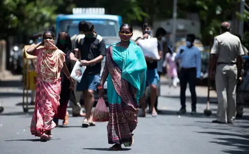 People buy essential commodities in a market at Worli village during a nationwide lockdown as a preventive measure against the spread of the COVID-19 coronavirus. Image by Manoej Paateel / Shutterstock. India, 2020.