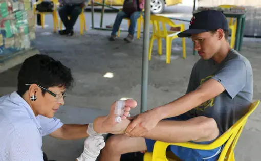 Marta Alcon tends to a Venezuelan caminante that&nbsp;arrived at her shelter in Los Patios,&nbsp;Colombia. Image by Patrick Ammerman. Colombia, 2019.