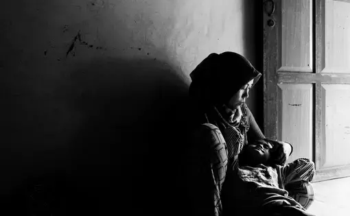 Asnia shares a tender moment with her daughter Dewi after work. Dewi is deaf and mute. Asnia works hard in the plantation to save money for her daughters treatment. Image by Xyza Cruz Bacani. Indonesia, 2018.