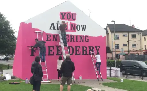 “You Are Now Entering Free Derry” Mural. The Free Derry mural, signifying police ‘no go’ zones during The Troubles, is painted pink for Pride. Photo by Julia Canney. Northern Ireland, 2018.