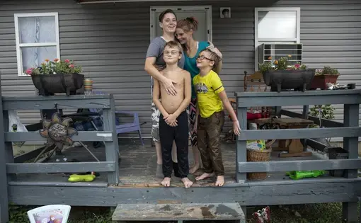 Tasha Lamm, 30, right, poses with her girlfriend, Alicia Mullins 22, and Lamm's sons, Donovyn, 8, left, and Gabriel Bonice, 7, in front of their home in Bidwell, Ohio, on Monday, July 27, 2020. Lamm dreams of taking her family and leaving Ohio, the scene of so much personal pain: "I'm ready to leave this hellhole and everyone in it because I know there's something better for me." Image by Wong Maye-E/AP Photo. United States, 2020.