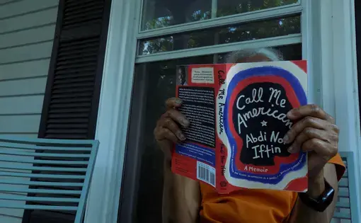 Yarmouth resident sits on her front porch while reading Abdi Nor Iftin’s memoir, Call Me American. Image by Francesca Bentley. United States, 2020.