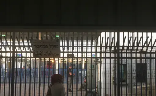 Israeli private security guards chat with Israel Defence Force (IDF) soldiers behind the bars at Qalandia checkpoint. Image by Matt Kennard. West Bank, 2016.