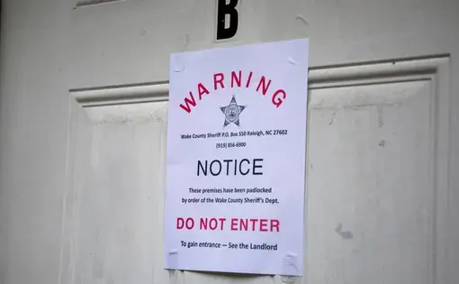 A padlock notice is taped to the door of an apartment, whose tenant was unavailable for comment, in late August in Raleigh, N.C. Image by Casey Toth. United States, 2020.