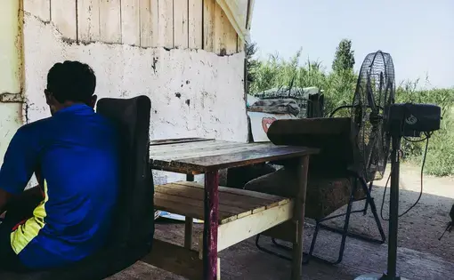 An unaccompanied minor sits in front of a migrants' shack in Marathona Village. Image by Divya Mishra. Greece, 2018.