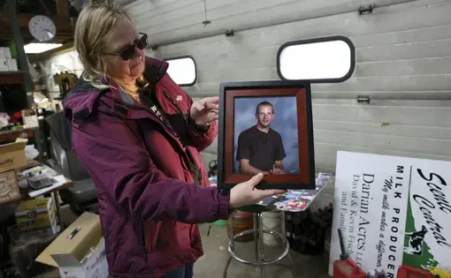 Amy Fischer is seen with a photo of her son, Brian, on her family’s 350-cow dairy farm, Darian Acres, in Rio, Wis., on Dec. 18, 2020. Brian died by suicide at the age of 33, on Dec. 21, 2016. The Fischers attribute his death to a combination of stress from work, a drinking problem and depression from a recent break-up. Dairy farmers and their advocates say numerous stressors are leading to a mental health crisis in their industry, including financial pressures, long hours, labor shortages and harsh weather.