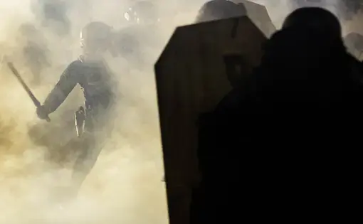 A Portland Police officer wields a billy club against a protester amidst a cloud of teargas  outside of the North precinct in Portland, Oregon.