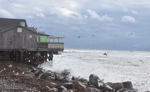 Waves crash against the coastline. There is a building on the coast.
