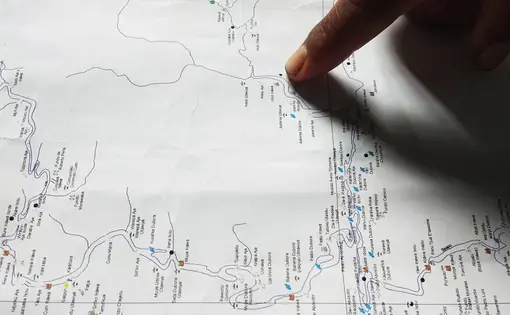 Someone points to a dot on a map.