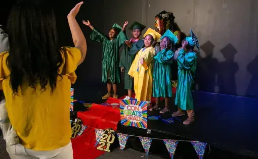 Tyra Johnson stands and cheers her three children on as they graduate from Medici Mediaspace.