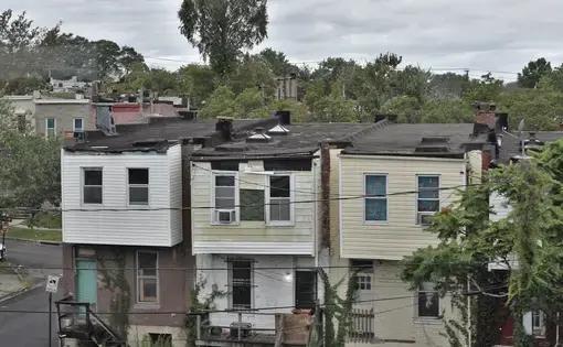Image of three dilapidated houses in Baltimore's Cherry Hill neighborhood as seen from the tram line.