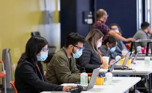 Volunteers sit masked a check-in table at a vaccination event in Chicago.