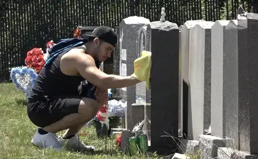 man kneeling beside headstones