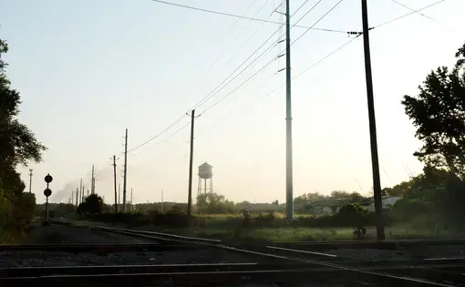 Image of a field with power lines and a water tower, a site where enslaved people were once bought and sold.