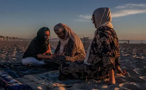 women sit on beach together