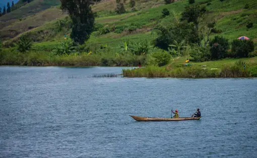 Two people paddle on a boat in a river.