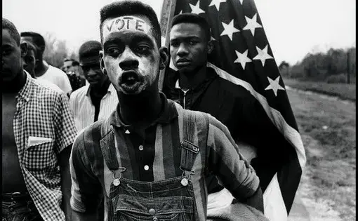A march featuring a young person with the word "VOTE" in face paint