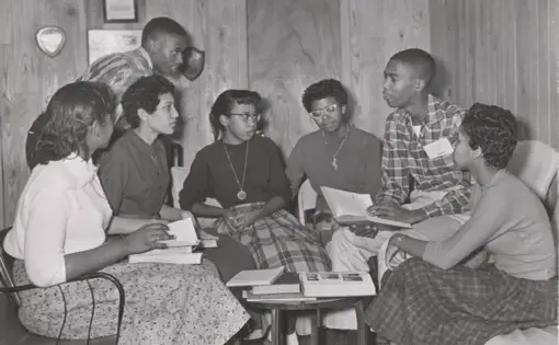 Seven students of the Little Rock Nine sit in a circle with books.