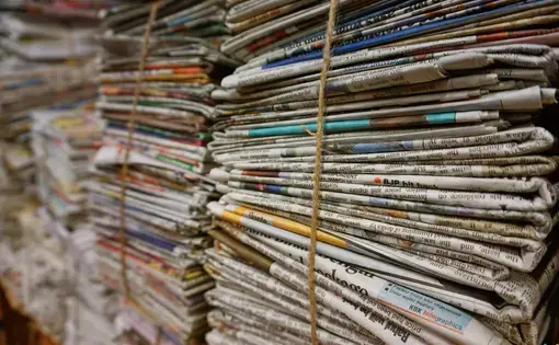 Tall stacks of newspapers bound together with string.