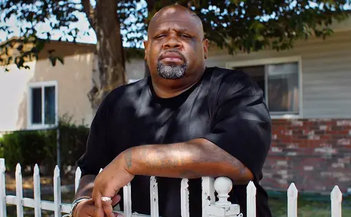 Melvin Smith stands outside his childhood home in Compton, California.