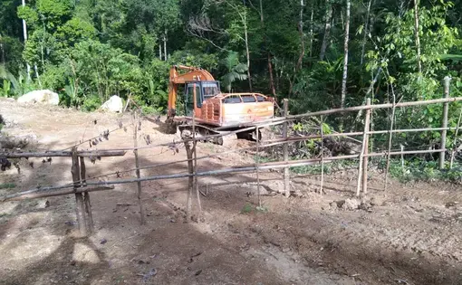 An excavator machine is being driven around a forest.