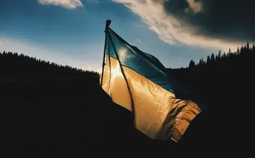 Ukrainian Flag in the wind in front of a silhouetted mountainscape