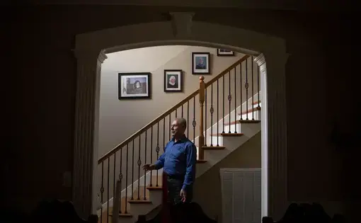 Yasin Kokoye stands near the entrance at his home