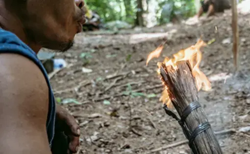 a man blow a torch in a forest