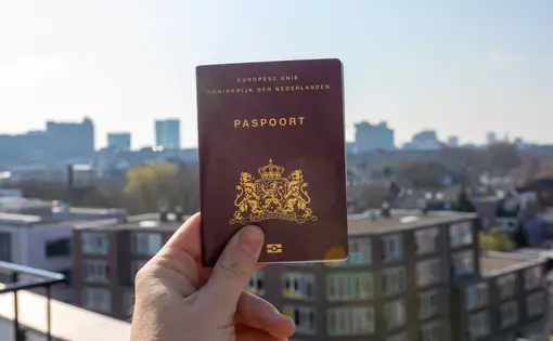 Dutch European paspoort with a clear blue sky and a city in the background