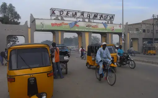 Bikers and cars roll under an archway