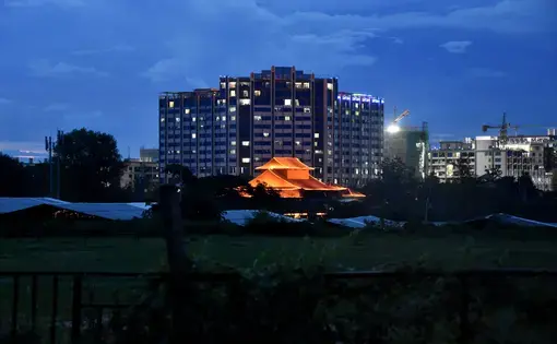 a lit up tent among concrete buildings at night time