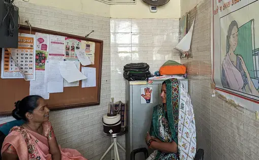 Two women sit in an exam room in India.