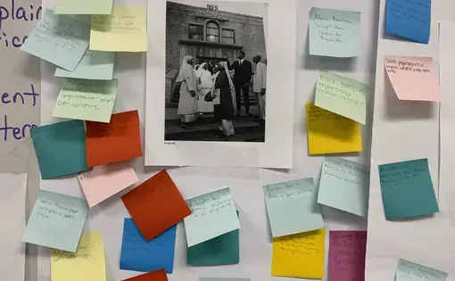 A Black and White photo of the Bronzeville neighborhood on a giant post-it and surrounded by small multicolor post its with student reflections on the image