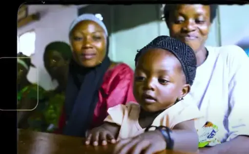 A young child is held by their mother while seated at a table