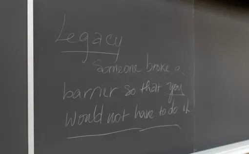 A close up image of a blackboard with the words "Legacy: Someone broke a barrier so that you wouldn't have to" in chalk.
