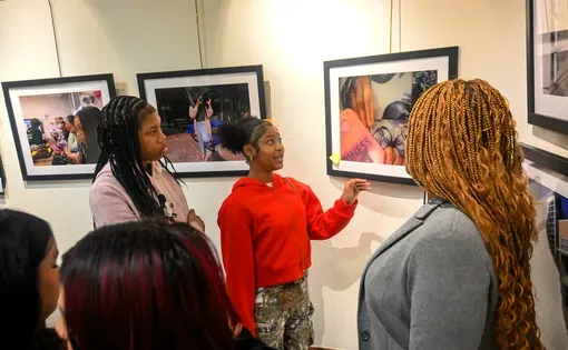 young people gather around a printed photograph at an exhibit