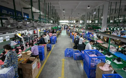 Eye-level view of a factory floor, where workers prepare packaging of products.