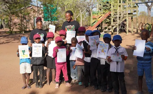 Children in the Bush Babies Environmental Education Program show off their coloring pages of meerkats. Image by Olivia Lockett. South Africa, 2025.