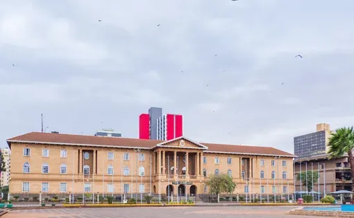 Nairobi, Kenya – Oct 08, 2022: The Judiciary Museum and the High Court of Kenya building, with birds circling above and modern high-rises in the background.