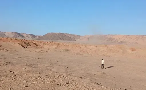 Djado, Niger. A man walks toward excavated pits at a mining site. Image by Amma Moussa.