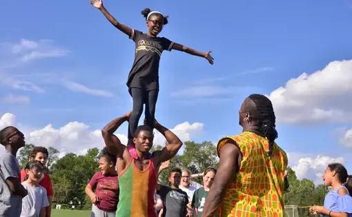 A Deal Middle School sixth grader balances on the shoulders of a Circus Kalabanté acrobat. Image by Dermot Tatlow. United States, 2018.