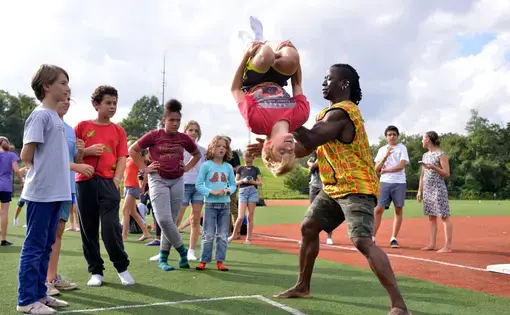 With help from Yamoussa, a Deal Middle School student completes a backflip. Image by Dermot Tatlow. United States, 2018.