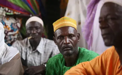 A resident of the village of Adouna, Niger, sits in a meeting with other villagers. Residents say Lutheran World Relief’s project to rebuild a dam near the village will increase usable farmland near the village and provide villagers with a way to get to market, thus increasing incomes.