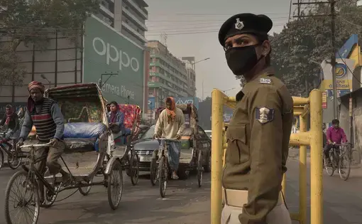 Traffic policewoman Sandhya Bhartj directs traffic in central Patna. Her cloth mask does little to protect her from the smallest particulate pollution. Image by Larry C. Price. India, 2018.